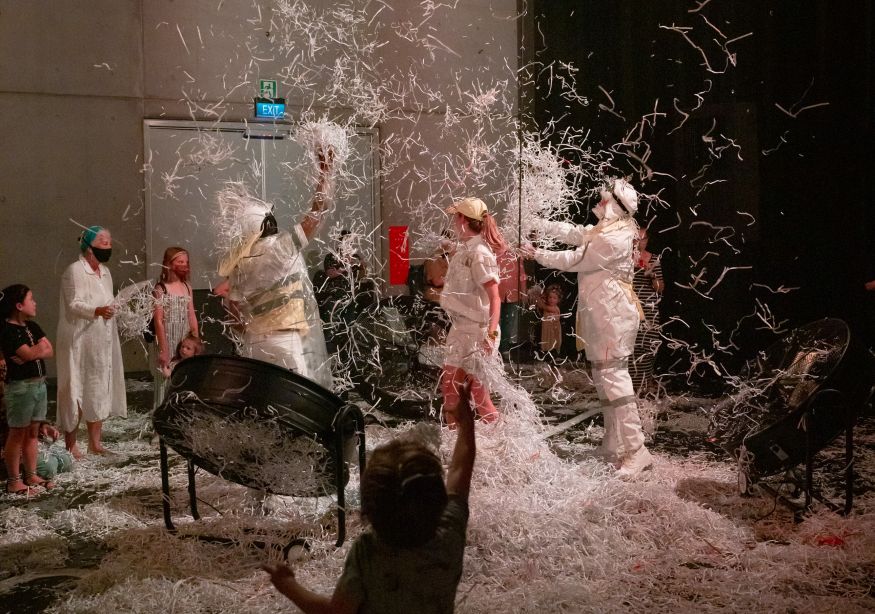 Image of children and adults playing in shredded paper at the DreamBIG festival.