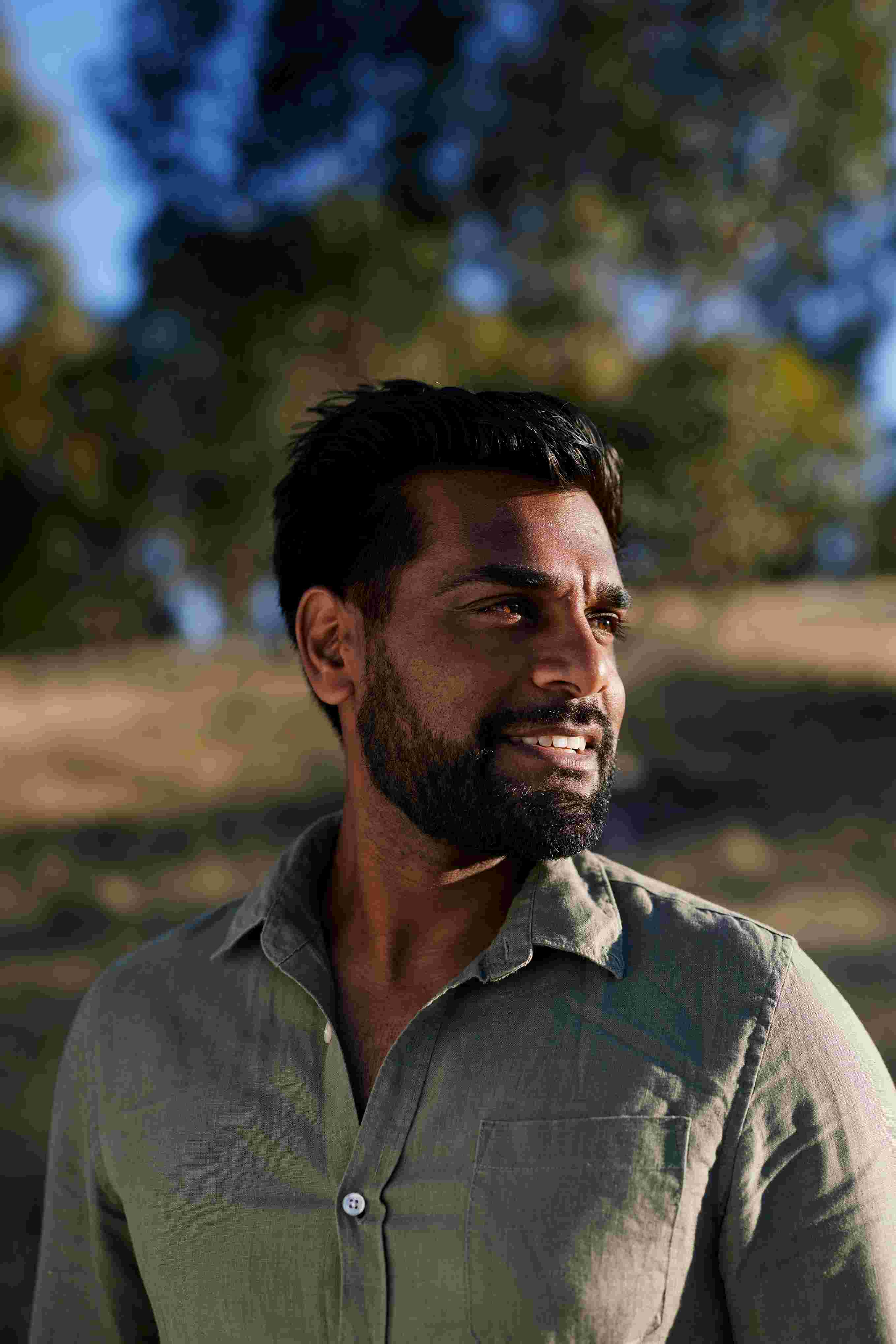 Image of Damien, he is wearing a khaki-coloured shirt and staring off into the distance.
