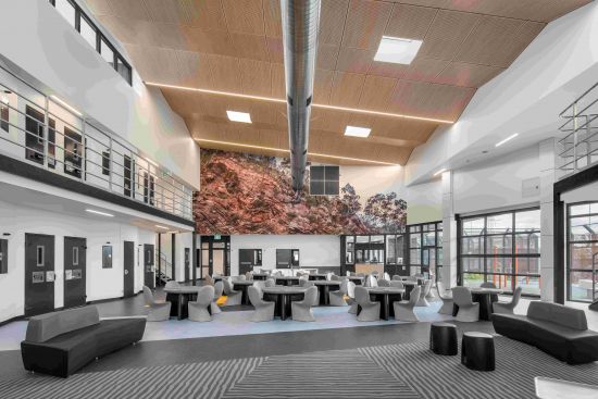 Image of new room at Yatala Labour Prison, with high ceilings, tables and chairs, and big picture of a rock face on one wall.