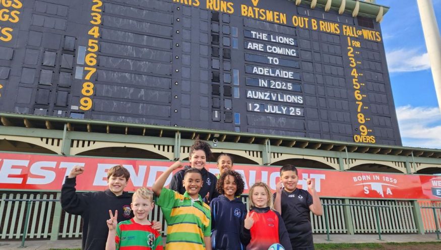 Image of a group of children dressed in rugby jerseys, in front of the Adelaide Oval scoreboard.