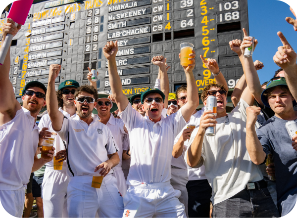 A group of Australian cricket fans celebrating in front of Adelaide Oval scoreboard