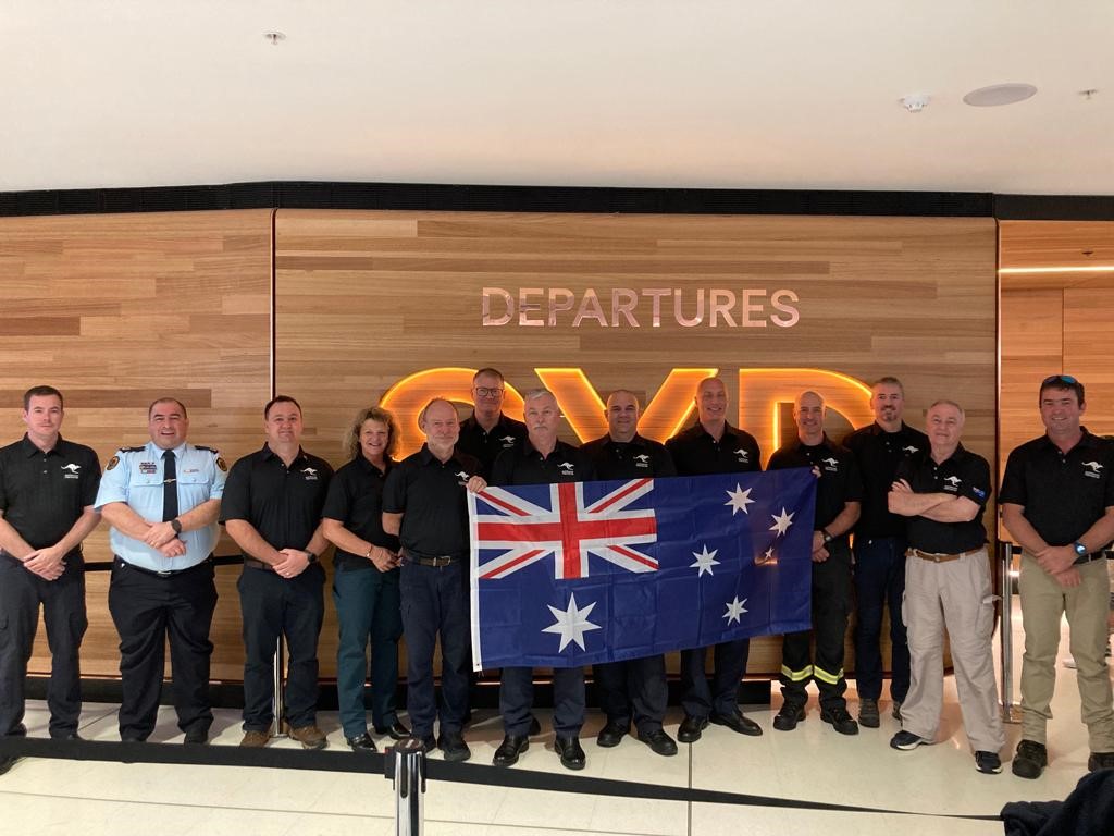 Image of firefighters line up at Sydney airport, holding an Australian flag.