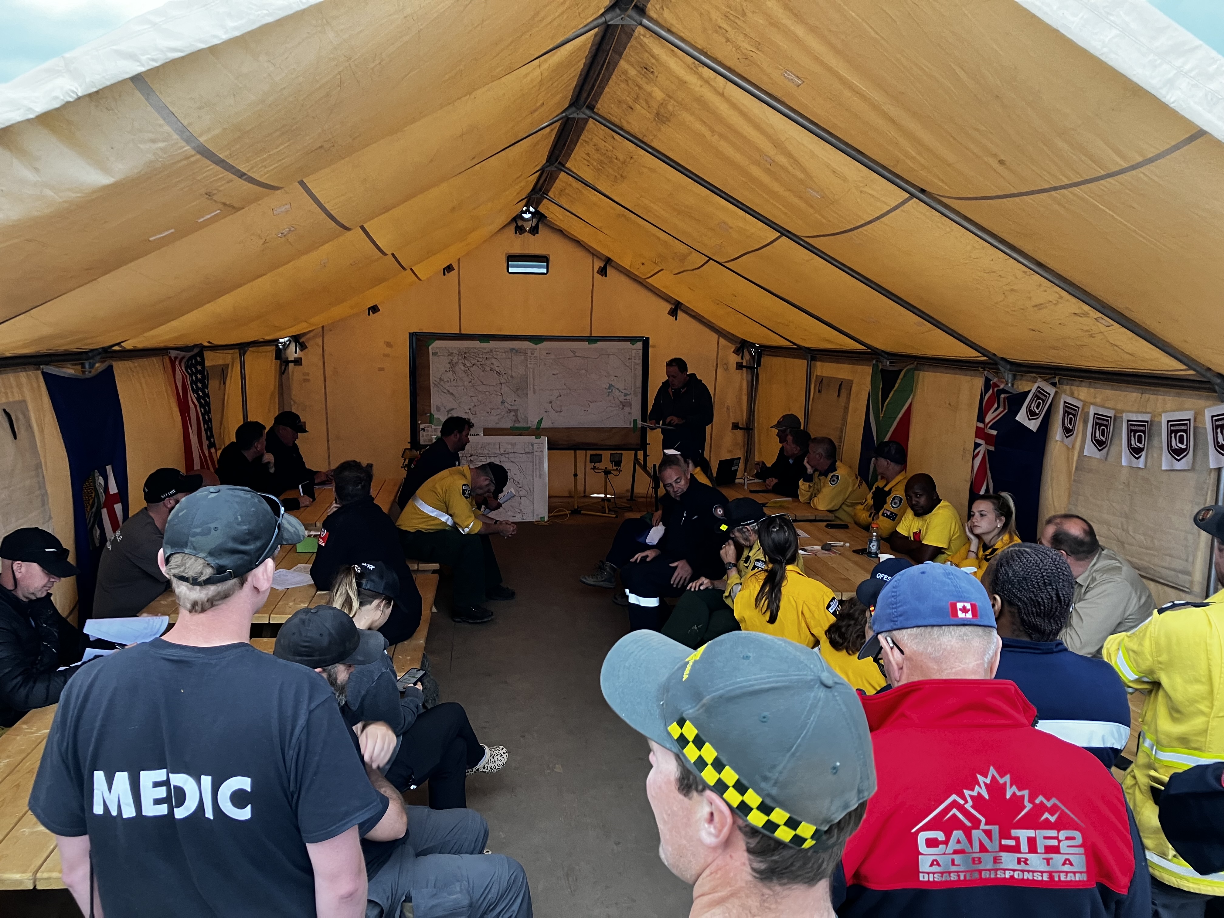 Image of a tent with an international fire fighting crew, having a meeting regarding the Canada wildfires.
