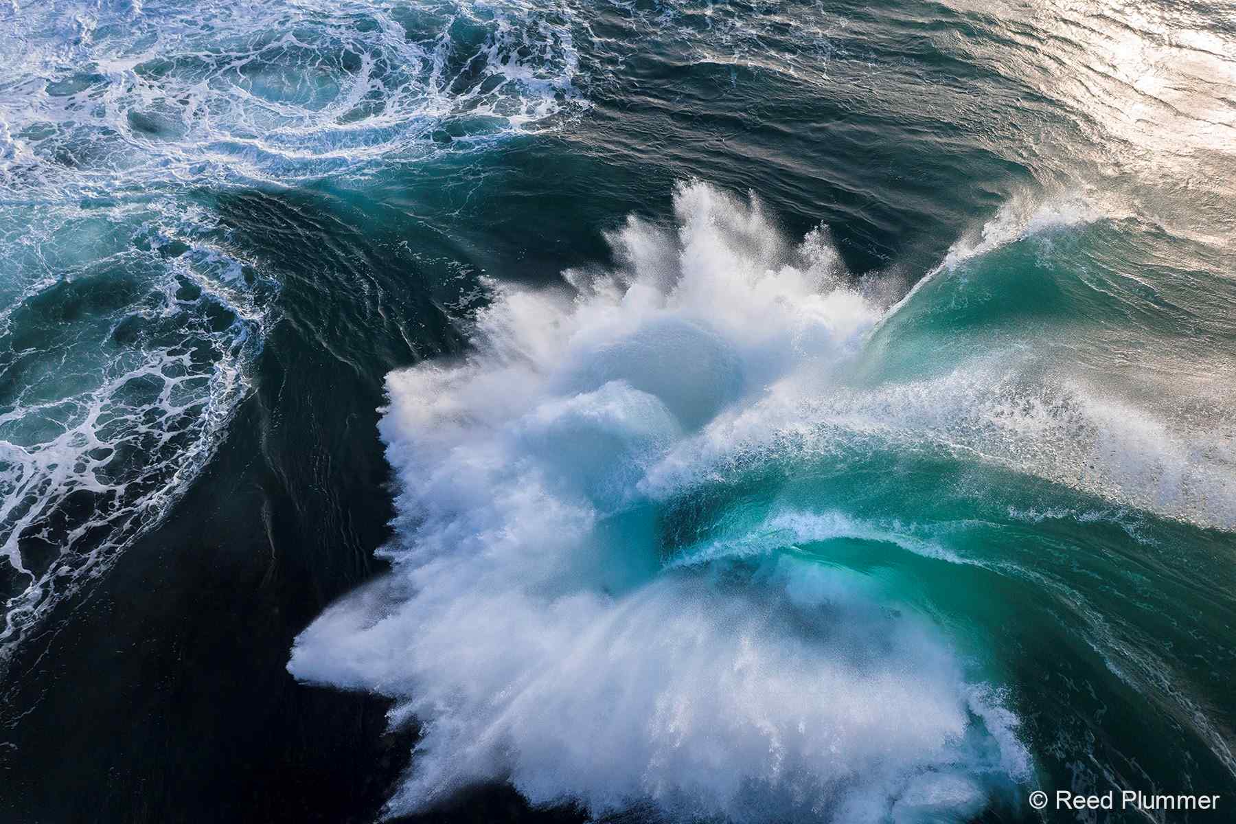 Image of waves crashing into each other, the water appears green and see-through, the waves are very large.