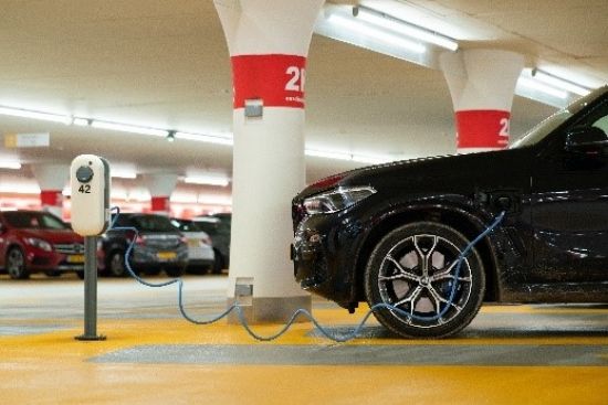 Image of an electric vehicle being charged, inside a carpark.