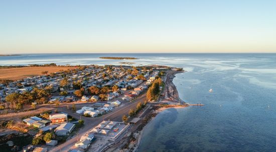 Image of Fisherman Bay, a small town on the coast, with a jetty and a beach, with streets of houses. 