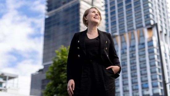 Image of Rachel Kidwell, Chief Executive Officer, TCPinpoint, looking into the distance, standing in front of a building.