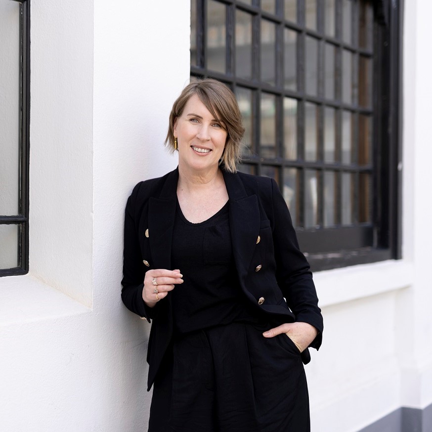 Rachel Kidwell, Chief Executive Officer, TCPinpoint, standing in front of a white building.