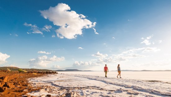 Image of two people walking on a coastline beach with blue pristine skies in Wudinna 