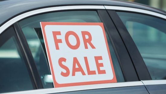 Image of a car for sale, it has a 'for sale' sign in the window.