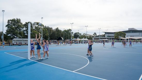 Netball players compete on newly upgraded outdoor courts at the Mile End Sports Complex, with multiple games underway across the precinct and spectators gathered in the background.