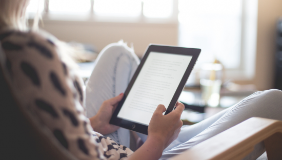 A woman holding an iPad reading an online book 