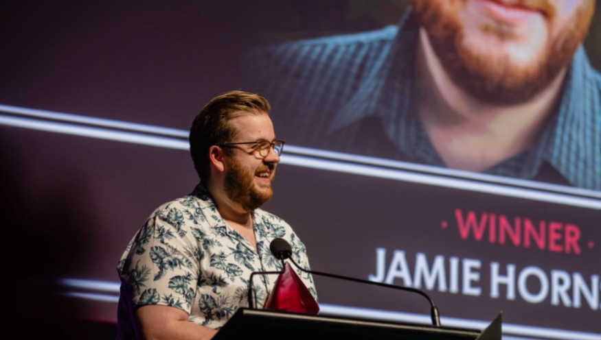 Jamie Hornsby pictured on stage accepting his 2022 Ruby Award