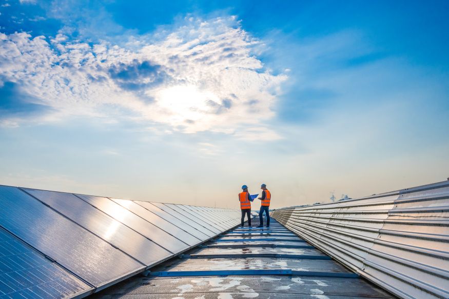 Image of two people inspecting panels on a roof top.