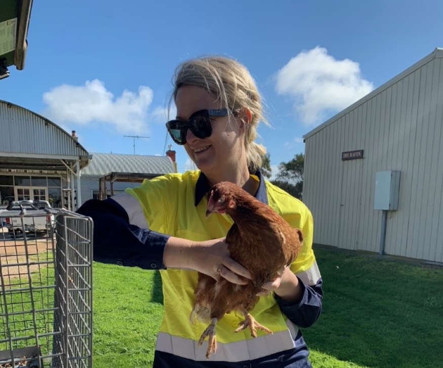 Image of female SA Health employee outside holding a chicken